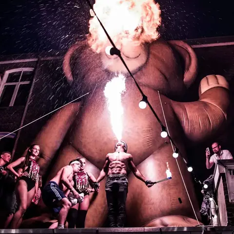 Vuurspuwer Nuno spuwt een vuurbal op een festivalplein voor een groot publiek