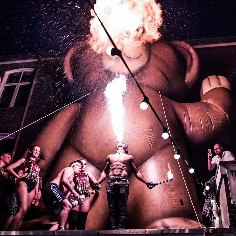 Vuurspuwer Nuno spuwt een vuurbal op een festivalplein voor een groot publiek
