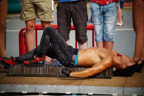 Fakiract op straat: twee toeschouwers staan op Nuno terwijl hij op het spijkerbed ligt