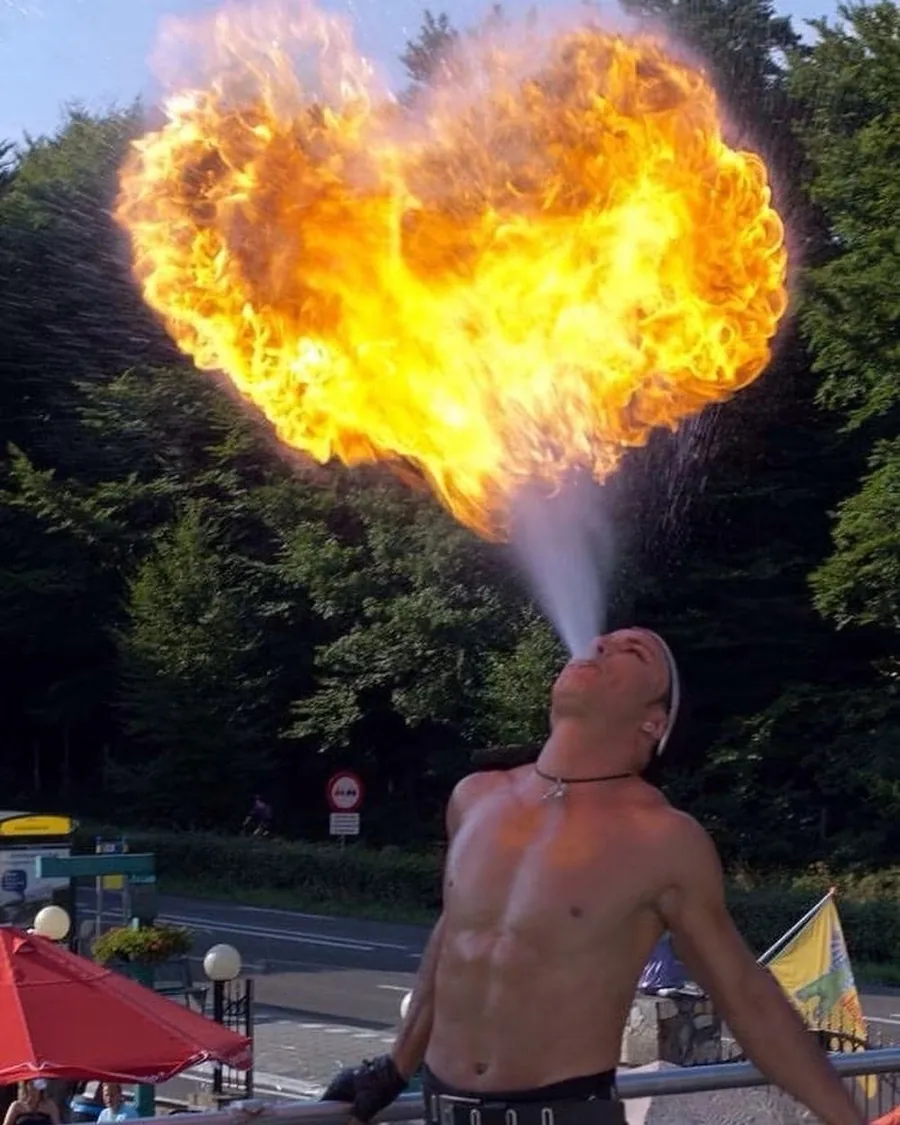 Vuurspuwer Nuno blaast een vuurbal in de vorm van een hart tegen de zomerlucht