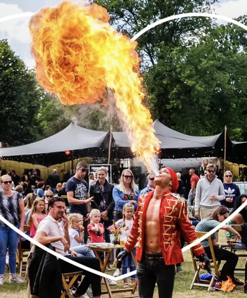 Vuurspuwer Nuno spuwt een vuurbal boven het publiek tijdens een festival overdag